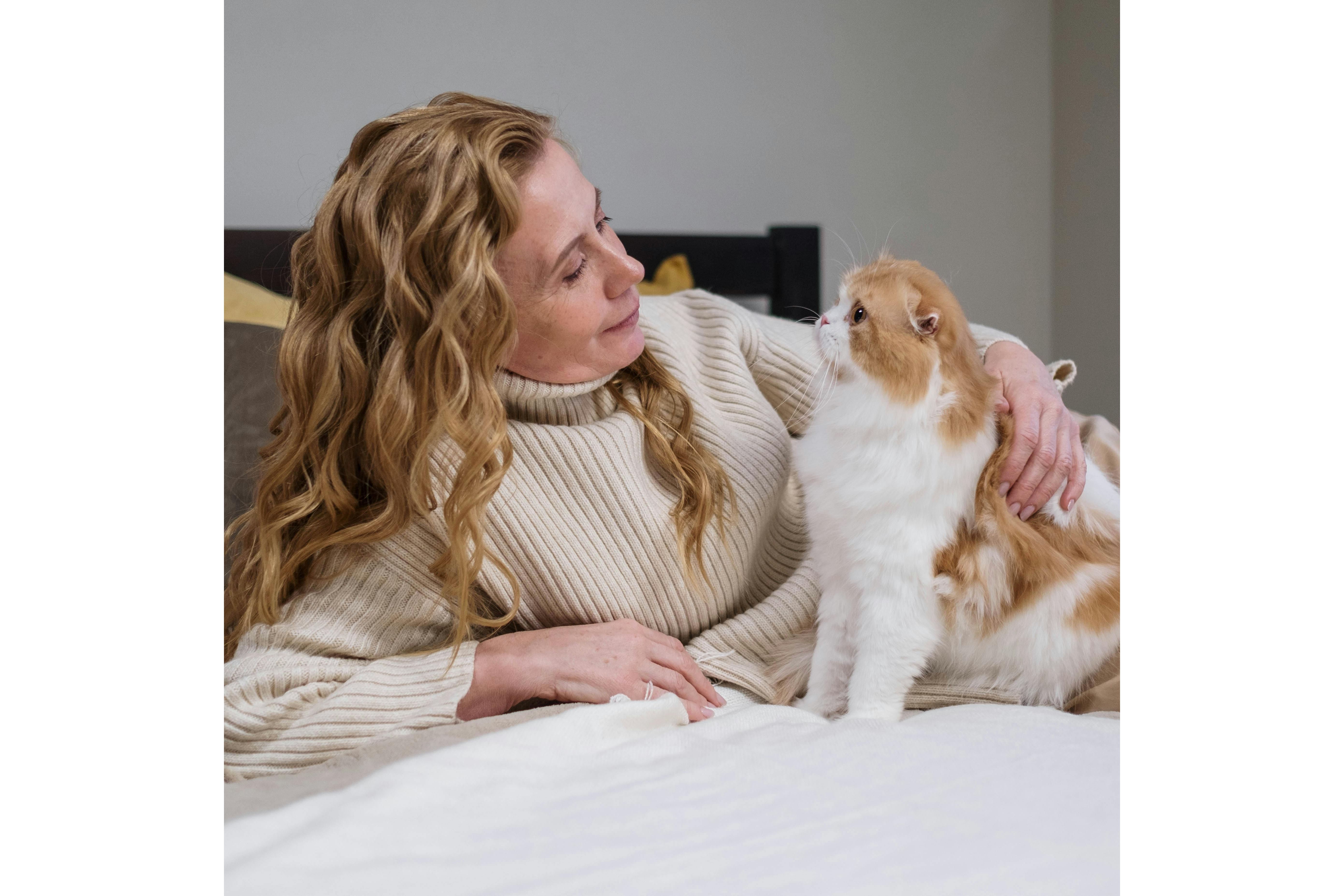 Mujer acostada en una cama con un gato. Foto: Pexels/cottonbro studio