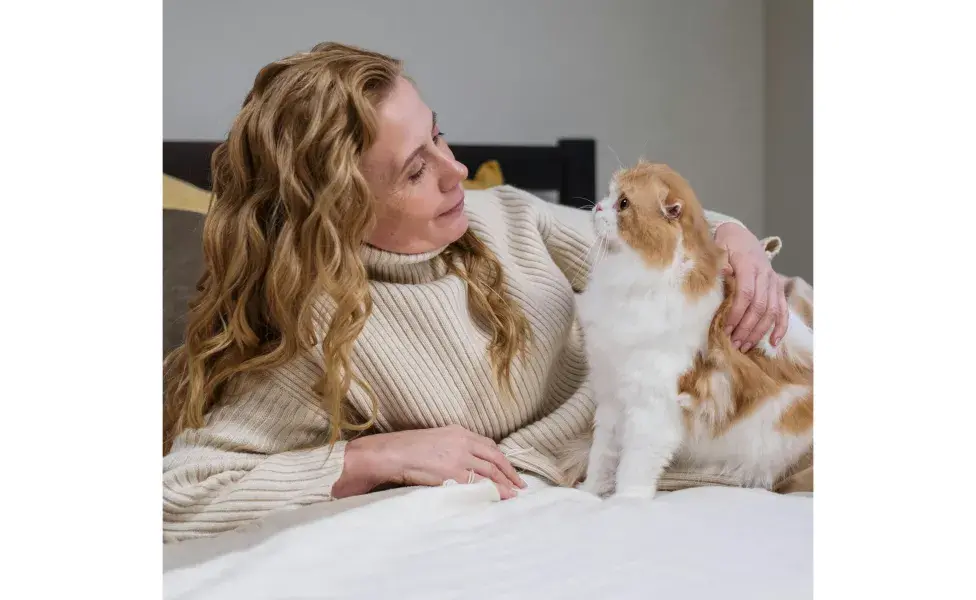 Mujer acostada en una cama con un gato. Foto: Pexels/cottonbro studio