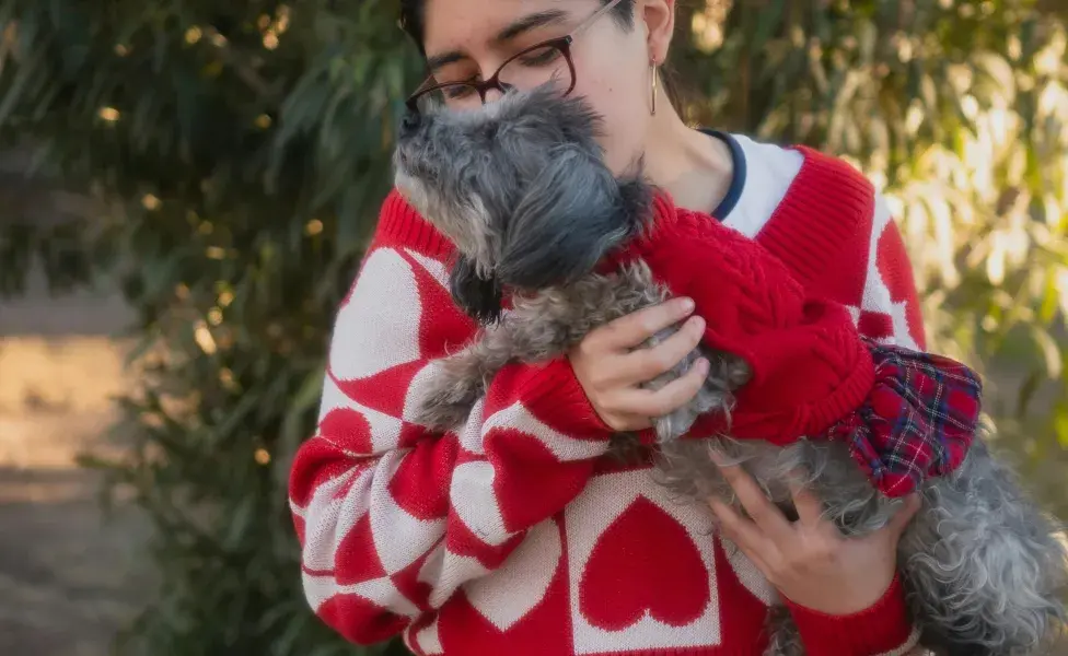 Mujer cargando a su perro. Foto: Pexels/Carlos Santiago