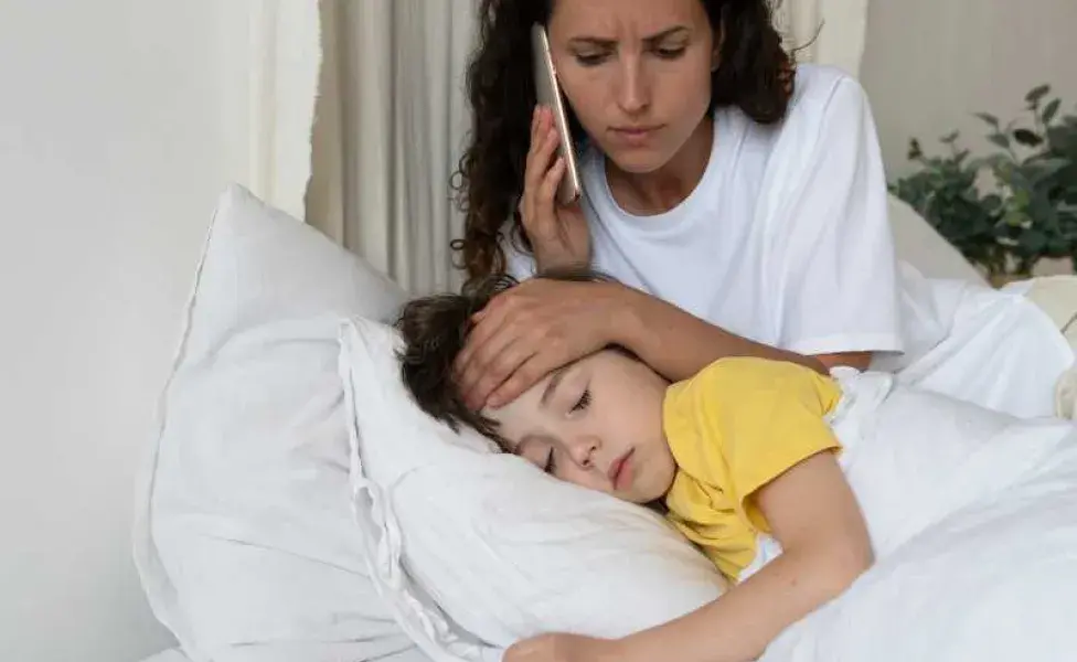 Niño enfermo en cama y su mamá cuidándolo. Foto: Envato/Dimaberlin